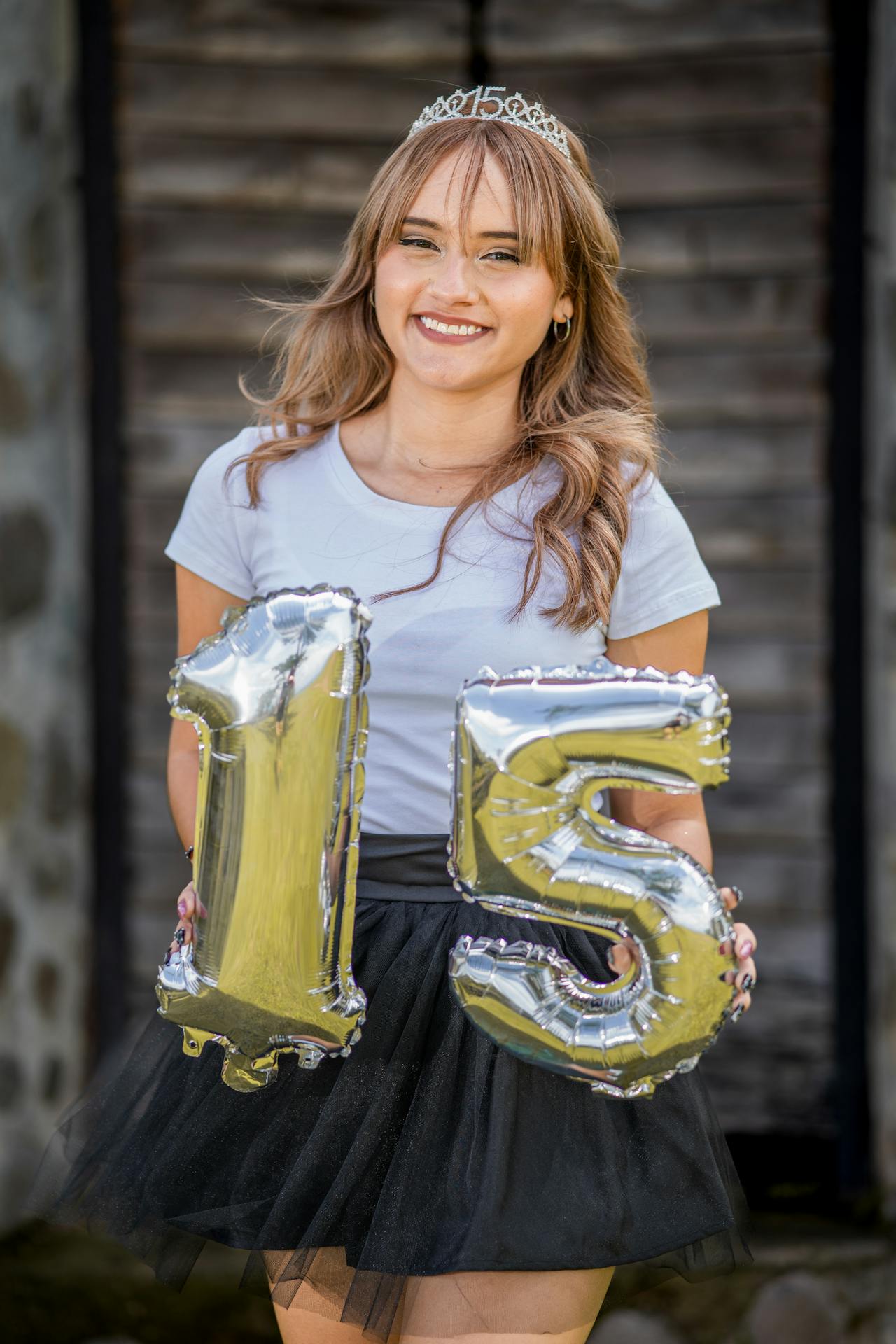 Quinceañera sonriendo con globos