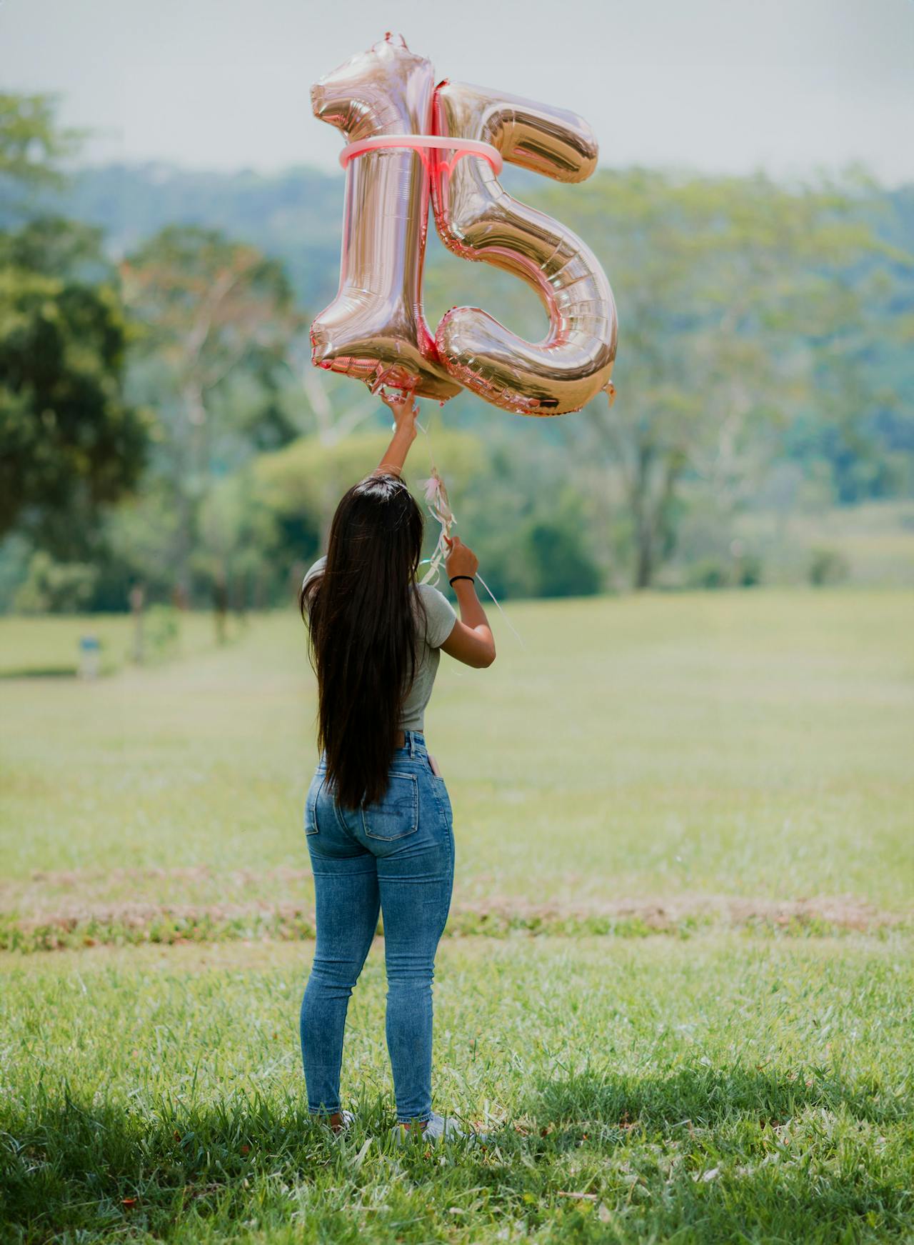 Quinceañera de espaldas con globos